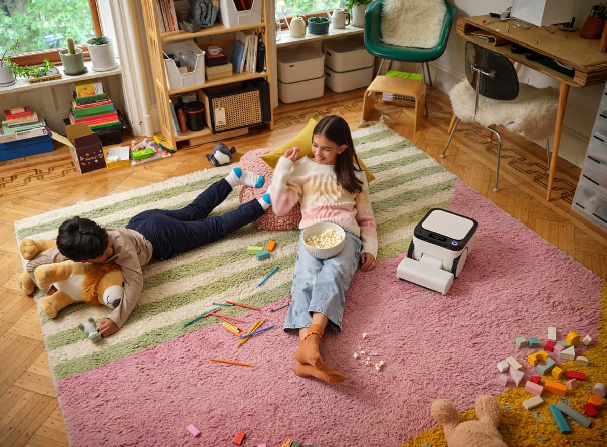 The Matic on a thick striped rug beside spilled popcorn while two children play