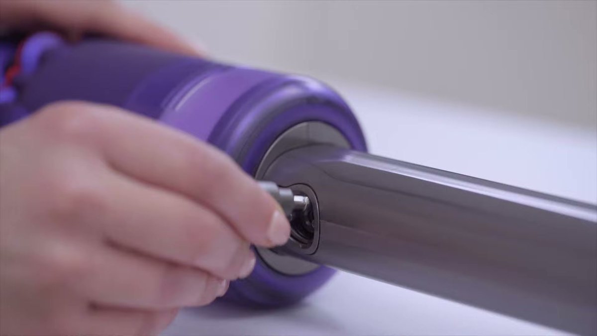 Close-up of hand attaching wand to Dyson Omni-Glide vacuum handle